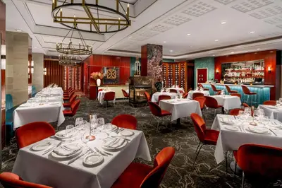 a restaurant with white tables and red chairs at DoubleTree by Hilton New York Midtown Fifth Ave in New York