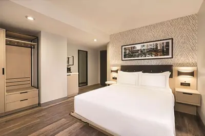 a bedroom with a large white bed and a kitchen at DoubleTree by Hilton New York Midtown Fifth Ave in New York