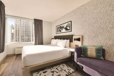 a hotel room with a large bed and a couch at DoubleTree by Hilton New York Midtown Fifth Ave in New York