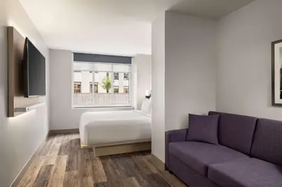 a bedroom with a bed and a couch and a window at DoubleTree by Hilton New York Midtown Fifth Ave in New York