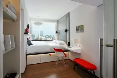 a bedroom with a bed and a desk with a red chair at citizenM New York Bowery in New York