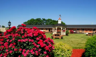a gazebo and flowers in front of a building at Weathervane Motor Court in Ronks