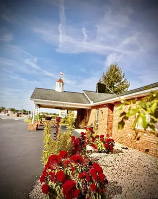 a church with red flowers in front of a building at Weathervane Motor Court in Ronks