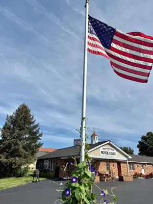 an american flag on a pole in front of a building at Weathervane Motor Court in Ronks