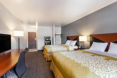 a hotel room with two beds and a flat screen tv at Days Inn & Suites by Wyndham Lancaster Amish Country in Lancaster