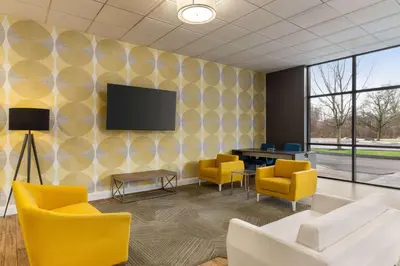 a waiting room with yellow chairs and a tv on a wall at Days Inn & Suites by Wyndham Lancaster Amish Country in Lancaster