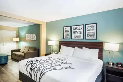 a hotel room with a bed and a chair at Sleep Inn & Suites Dunmore in Dunmore