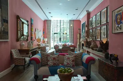 a living room with pink walls and a couch and chairs at Crosby Street Hotel in New York