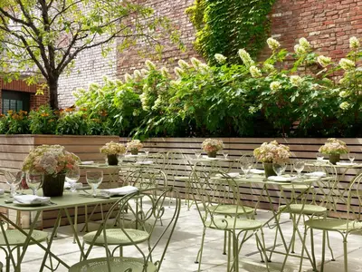 a group of tables and chairs in a garden at Crosby Street Hotel in New York