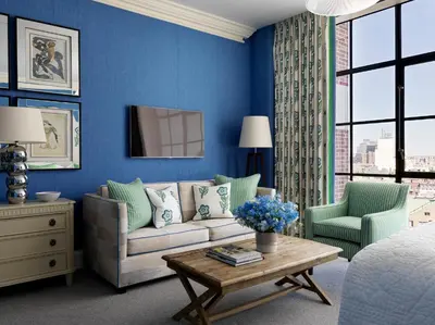 a blue living room with a couch and two chairs at Crosby Street Hotel in New York