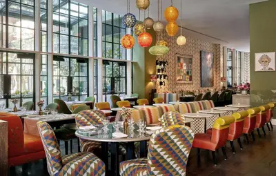 a restaurant with tables and chairs and windows at Crosby Street Hotel in New York