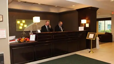 two men standing at a reception desk in a hotel lobby at Holiday Inn Budd Lake - Rockaway Area by IHG in Budd Lake