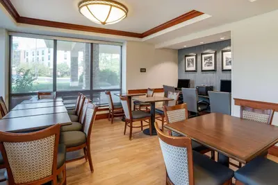 a restaurant with tables and chairs and a large window at Comfort Inn & Suites Newark - Wilmington in Newark