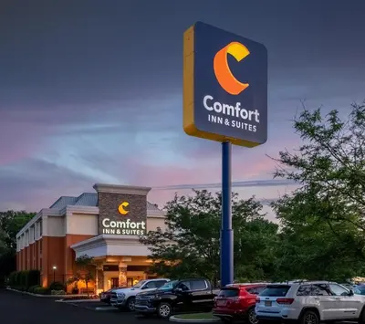 a sign for a hotel with cars parked in a parking lot at Comfort Inn & Suites Newark - Wilmington in Newark
