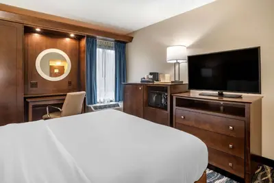 a hotel room with a bed and a flat screen tv at Comfort Inn & Suites Newark - Wilmington in Newark