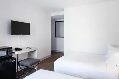 a hotel room with a bed and a desk with a television at The Gatsby Hotel in New York