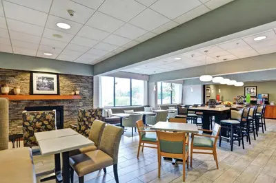 a restaurant with tables and chairs and a fireplace at Hampton Inn Lewisburg in Lewisburg