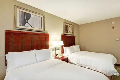 two beds in a hotel room with white sheets at Hampton Inn Lewisburg in Lewisburg