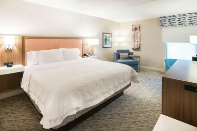 a hotel room with a large bed and a chair at Hampton Inn Clarks Summit in Clarks Summit