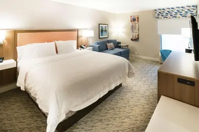 a hotel room with a large bed and a blue couch at Hampton Inn Clarks Summit in Clarks Summit