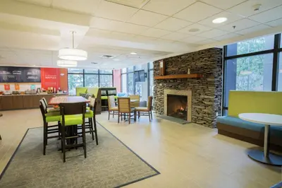 a lobby with a fireplace and tables and chairs at Hampton Inn Clarks Summit in Clarks Summit