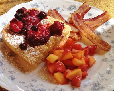 a plate of food with toast and fruit and french fries at Caldwell House Bed and Breakfast in Salisbury Mills