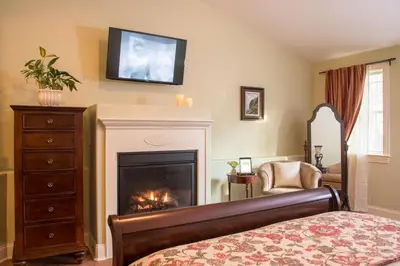 a bedroom with a fireplace and a tv on the wall at Caldwell House Bed and Breakfast in Salisbury Mills