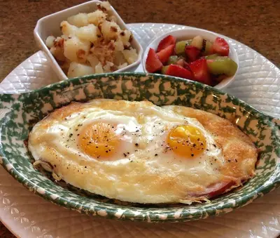a plate with a fried egg and a bowl of fruit at Caldwell House Bed and Breakfast in Salisbury Mills