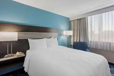 a large bed in a hotel room with a blue wall at Best Western Rutgers University Hotel in East Brunswick