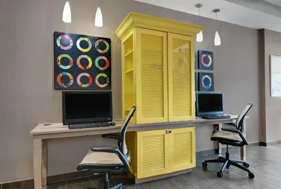 a yellow office with two chairs and a desk with a laptop at Home2 Suites By Hilton Bordentown in Bordentown