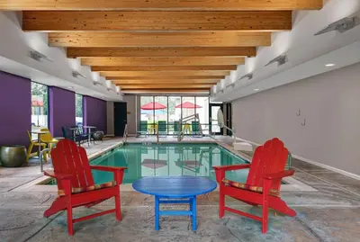 a swimming pool with two red chairs and a blue table at Home2 Suites By Hilton Bordentown in Bordentown