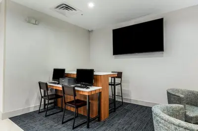 a room with a desk with chairs and a tv at Holiday Inn Express & Suites Jersey City North - Hoboken by IHG in Jersey City