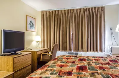 a hotel room with a bed and a flat screen tv at Relax Inn in Lewisburg