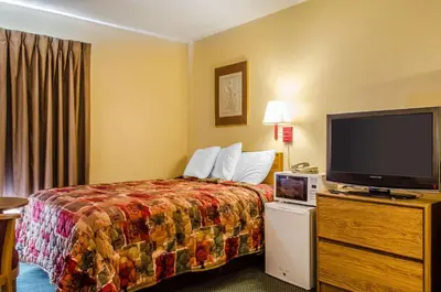 a hotel room with a bed and a flat screen tv at Relax Inn in Lewisburg