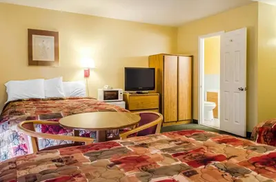 a hotel room with two beds and a table and a tv at Relax Inn in Lewisburg