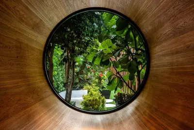 a round mirror on a wall with trees and plants at Dream Downtown, by Hyatt in New York