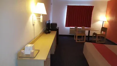 a hotel room with a bed and a desk with a television at Red Carpet Inn in Gibbstown