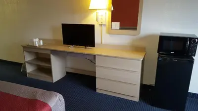 a desk in a hotel room with a television on it at Red Carpet Inn in Gibbstown