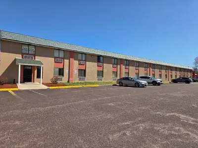 a large building with cars parked in a parking lot at Red Carpet Inn in Gibbstown