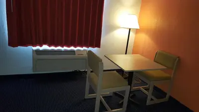 a room with a desk and a table and chairs at Red Carpet Inn in Gibbstown