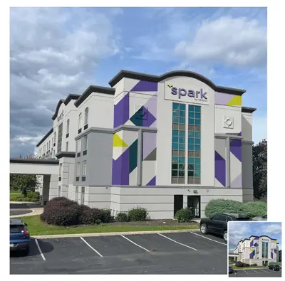 a parking lot in front of a spark building at Spark by Hilton Mechanicsburg in Mechanicsburg