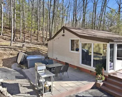 a tiny house with a patio and a grill at Pocono cabin with hot tub and private pool at Shawnee Mtn in East Stroudsburg