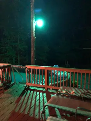 a wooden bench sitting on a deck at night at Pocono cabin with hot tub and private pool at Shawnee Mtn in East Stroudsburg