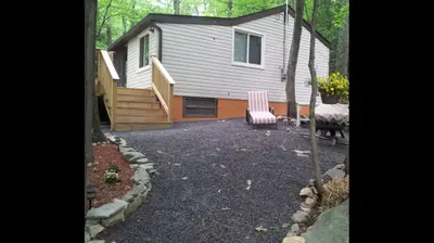 a house with a staircase and a chair in a yard at Pocono cabin with hot tub and private pool at Shawnee Mtn in East Stroudsburg