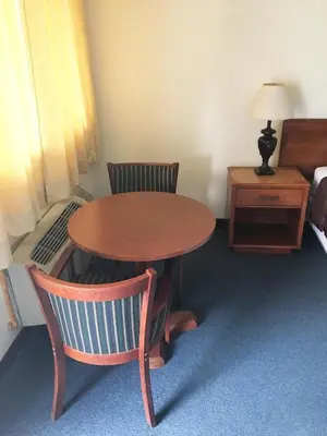 a room with a table and two chairs and a bed at Village Motel in Ellenville
