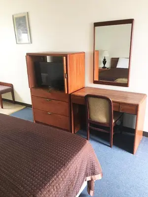 a bedroom with a desk and a mirror and a bed at Village Motel in Ellenville