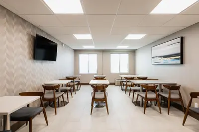 a room with tables and chairs and a flat screen tv at Garden Executive Hotel in South Plainfield