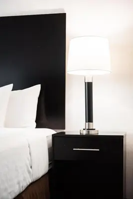 a lamp on a night stand next to a bed at Garden Executive Hotel in South Plainfield