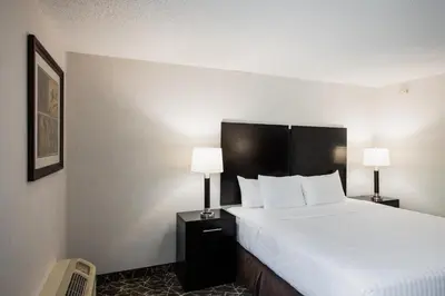 a hotel room with a large bed and two lamps at Garden Executive Hotel in South Plainfield