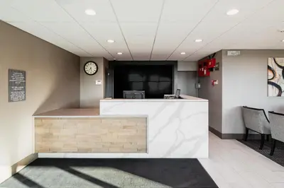 a lobby with a counter with a clock on the wall at Garden Executive Hotel in South Plainfield